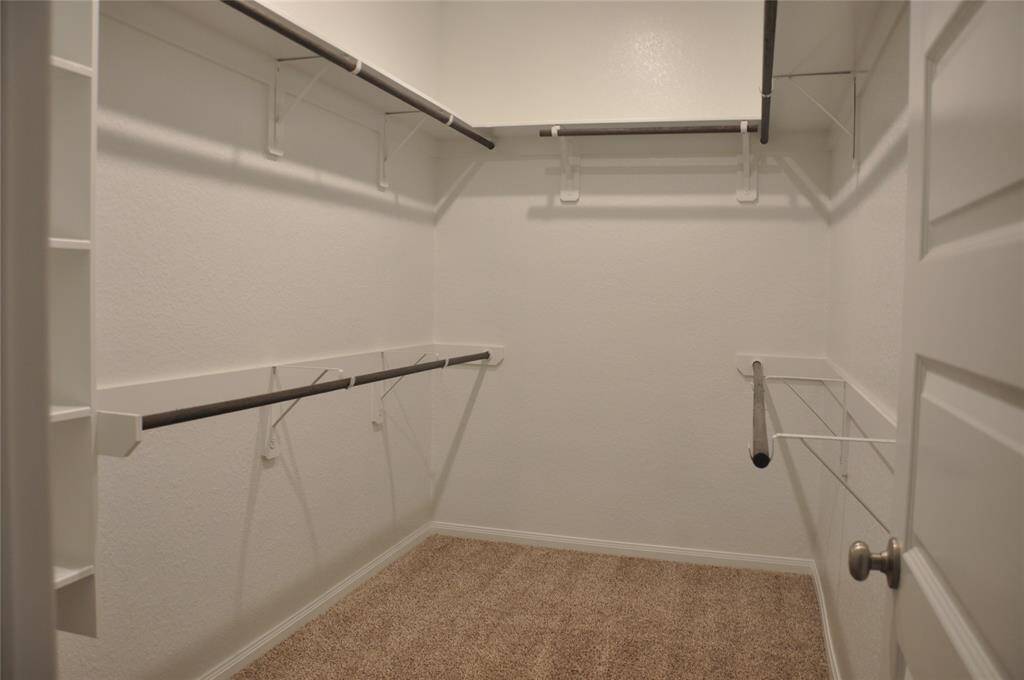 Walk-in closet in primary bedroom with built-in shelf.