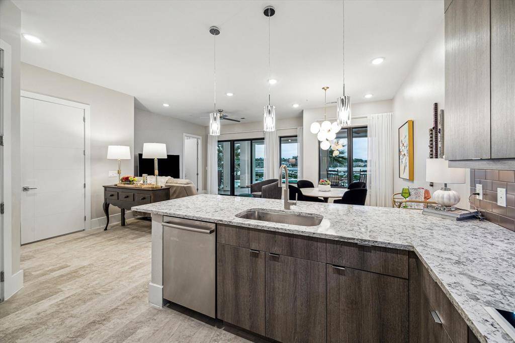 A well-appointed kitchen with sleek brown cabinets with granite countertops and stainless steel appliances.