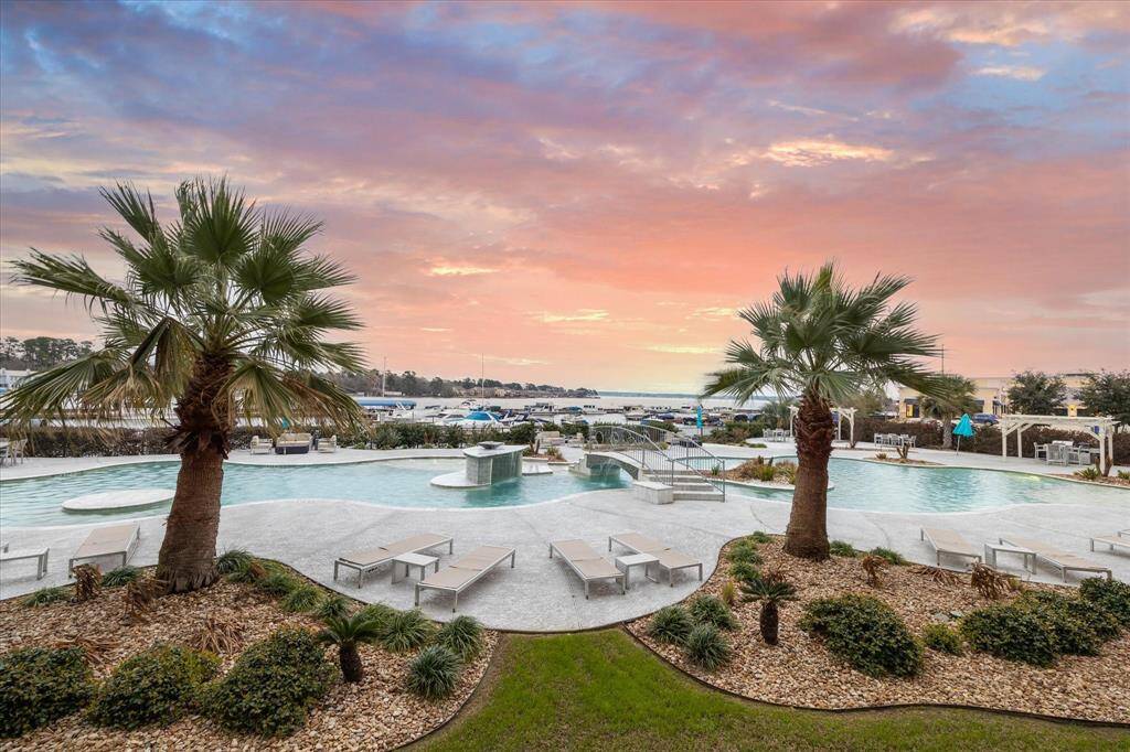Fabulous pool view with palm trees and a winding crystal blue pool next to the waterfront.