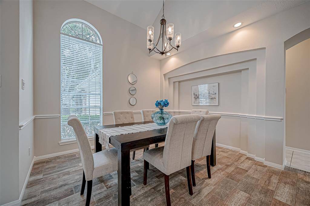 Every meal feels like a special occasion in this elegant dining area, where natural light pours in through the tall arched window, creating a warm and inviting atmosphere. Whether you're hosting a lively dinner party or enjoying a quiet meal with loved ones, the sophisticated built-in wall detail and stylish chandelier add just the right touch of charm.