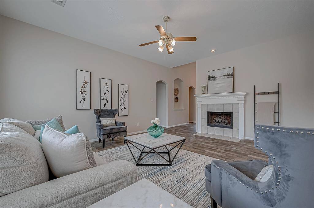 Gather your loved ones in this spacious living area, where the warmth of the beautiful fireplace and the gentle breeze from the ceiling fan create the perfect setting for comfort, relaxation, and making cherished memories.