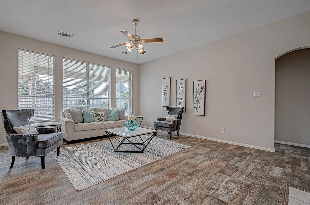 Step into this inviting living space, where the warmth of the wood-look tile flooring and soft neutral tones create the perfect balance of style and comfort, making every moment at home feel effortlessly cozy.