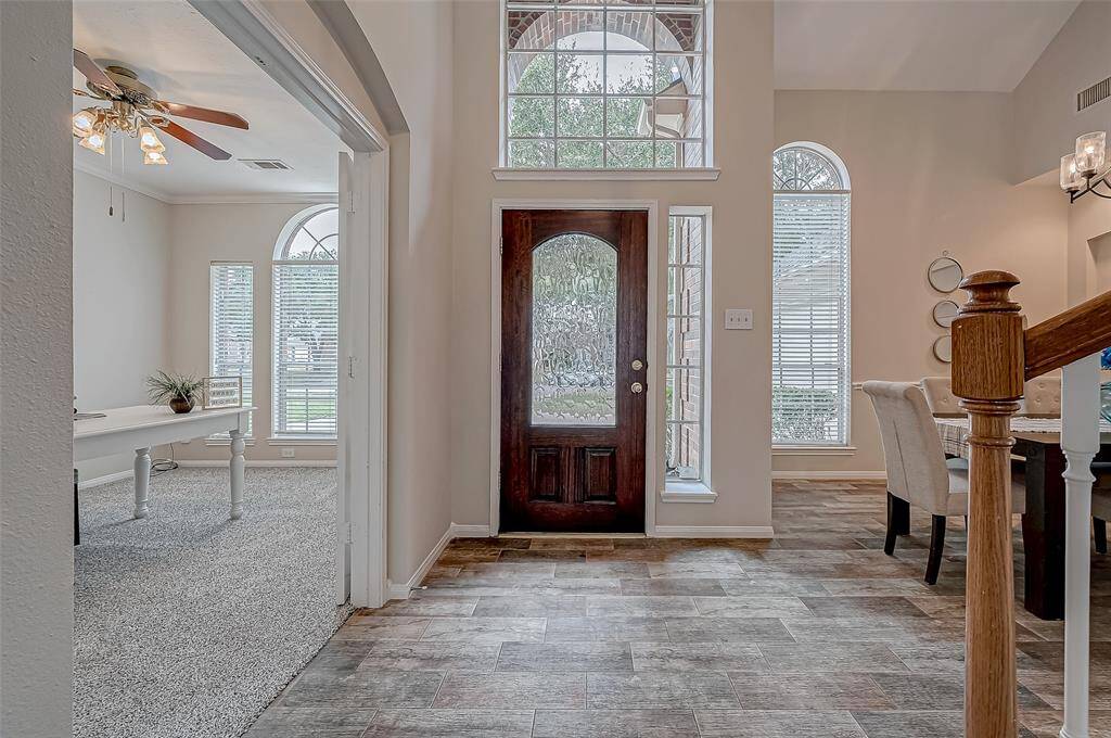 As you close the door, you will feel an immediate sense of comfort, thanks to the natural light streaming through the elegant glass panels. The high ceilings and windows create an open, airy atmosphere that makes the space feel both grand and inviting. With beautiful wood-look tile flooring that flows seamlessly into the main living areas, this entryway sets the perfect tone for the sophistication and charm that awaits throughout the home.