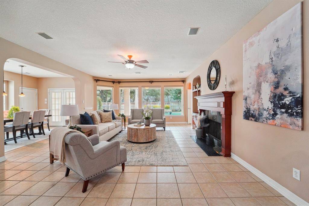 Relax or entertain, this lovely family room provides the perfect space for both with tile flooring, neutral paint, a gas-log fireplace, and picture-perfect views of the patio, pool, and yard.