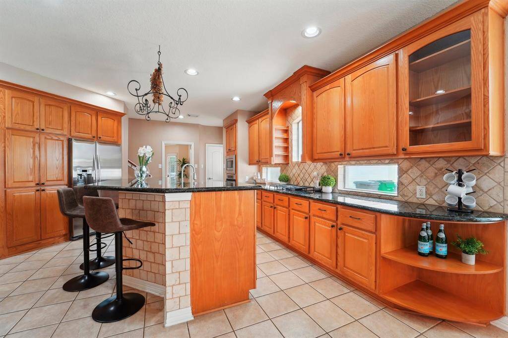 Show off your culinary skills in this dreamy island kitchen. Find rich wood cabinetry, granite countertops, tile backsplash, countertop windows, sleek stainless steel appliances, newly installed stove 2025 and a huge walk-in pantry.