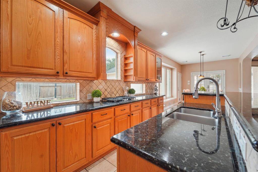 This kitchen boasts unique features, including countertop windows that fill the space with natural light—perfect for keeping an eye on the kids playing basketball in the auto court (hoop included!). Thoughtful details like built-in spice racks for effortless organization and a raised dishwasher for convenient loading and unloading add both style and functionality.