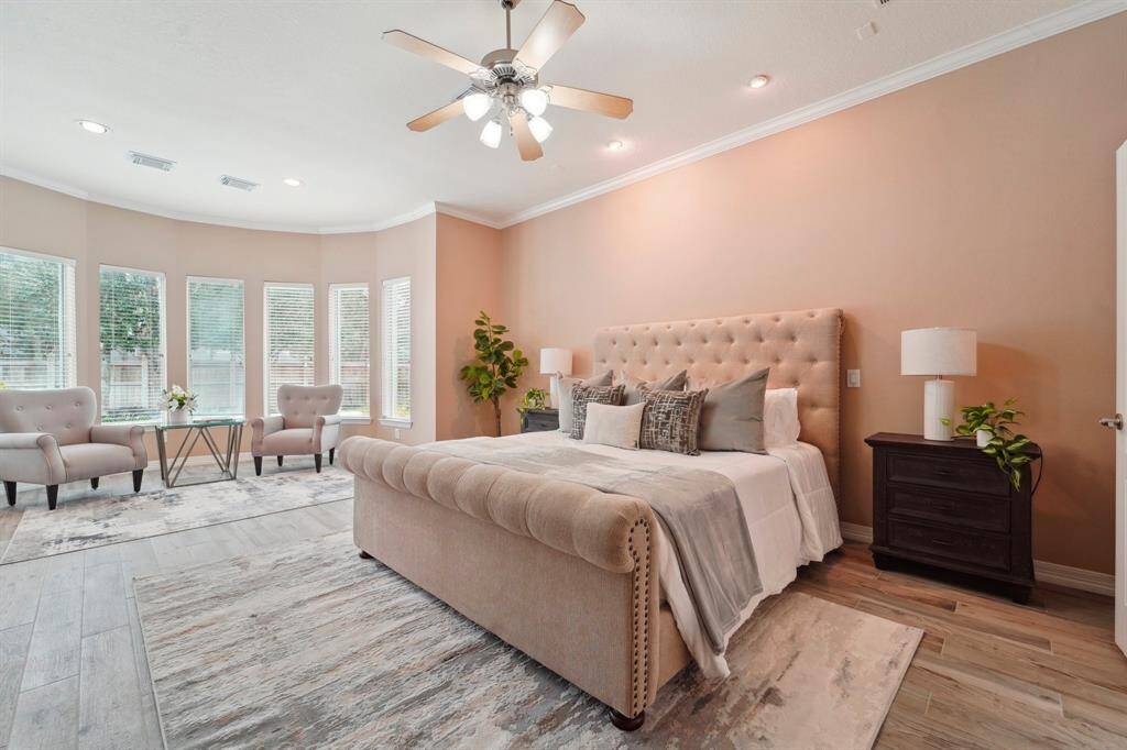 Unwind in this expansive owner's suite, where brand-new Luxury Vinyl Plank Flooring (LVP) installed in February 2025 adds both style and durability. Soft neutral tones, elegant crown molding, recessed lighting, and a cooling ceiling fan enhance the serene ambiance. A wall of bay windows showcases breathtaking views of the yard and pool.