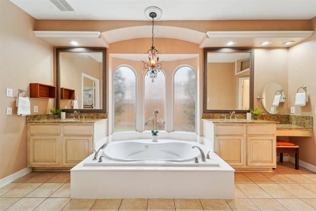 Unwind and indulge in this luxurious soaking tub, featuring dual fixtures for added convenience and a chic chandelier overhead, creating the perfect ambiance for relaxation. Upgraded in 2021.