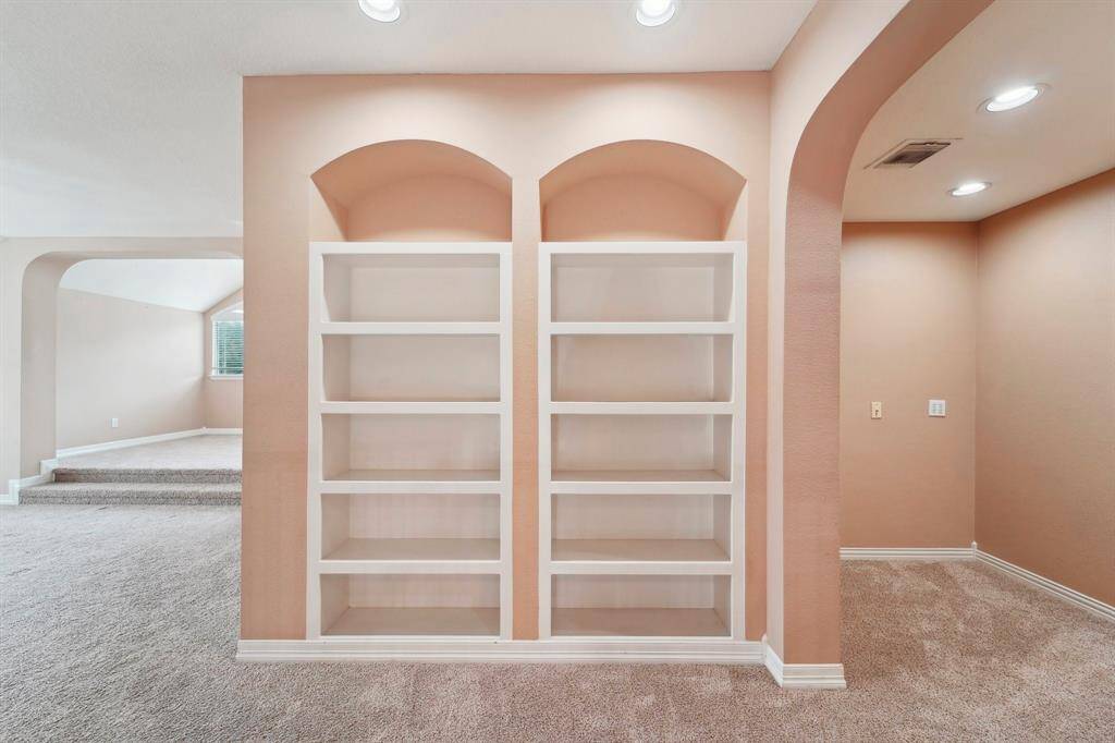 Built-in shelving offers the perfect space to organize books, games, toys, and more. To the right, a separate nook provides a quiet retreat for homework or study, while to the left, an additional bookcase cleverly opens to reveal hidden storage, combining functionality with thoughtful design.