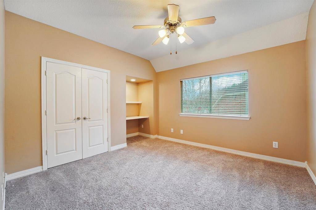 Family or guests will rest comfortably in this spacious guest bedroom with plush carpet, neutral paint, a built-in desk and shelving, a large closet and easy access to a full bathroom.