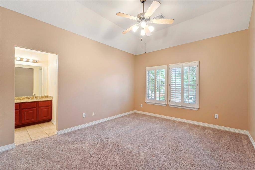 Guests will feel right at home in this spacious suite. This spacious bedroom offers plush carpet, neutral paint, a raised ceiling with lit ceiling fan, wood-shutters on the windows, a large closet and ensuite access to a full bathroom.