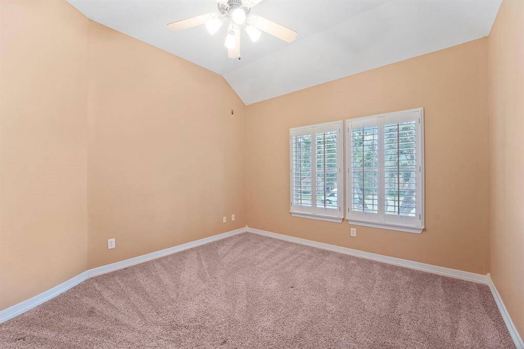 A raised ceiling with a lit fan, wood shuttered windows, plush carpet and ample space for personal touches make this guest bedroom an inviting space for family and friends.