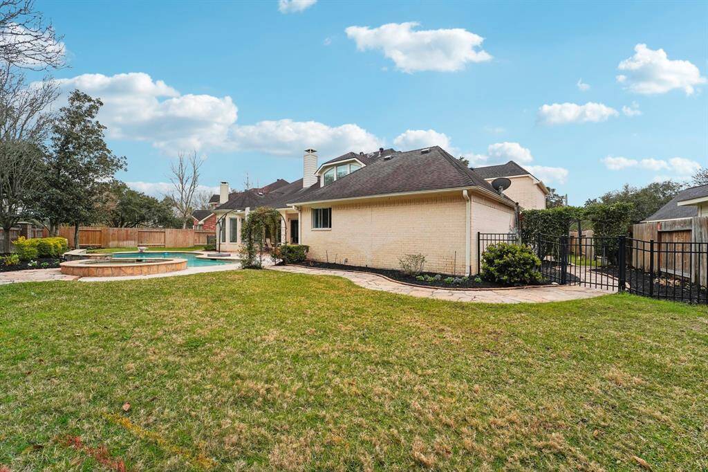 An expansive grassy lawn, enhanced by a WiFi-controlled Rachio Sprinkler System, offers the perfect space for outdoor play. Fenced side yards and stone paver walkways provide both privacy and charm, while mature landscaping, picturesque arbors, and a sparkling in-ground pool and spa create a serene backyard oasis.