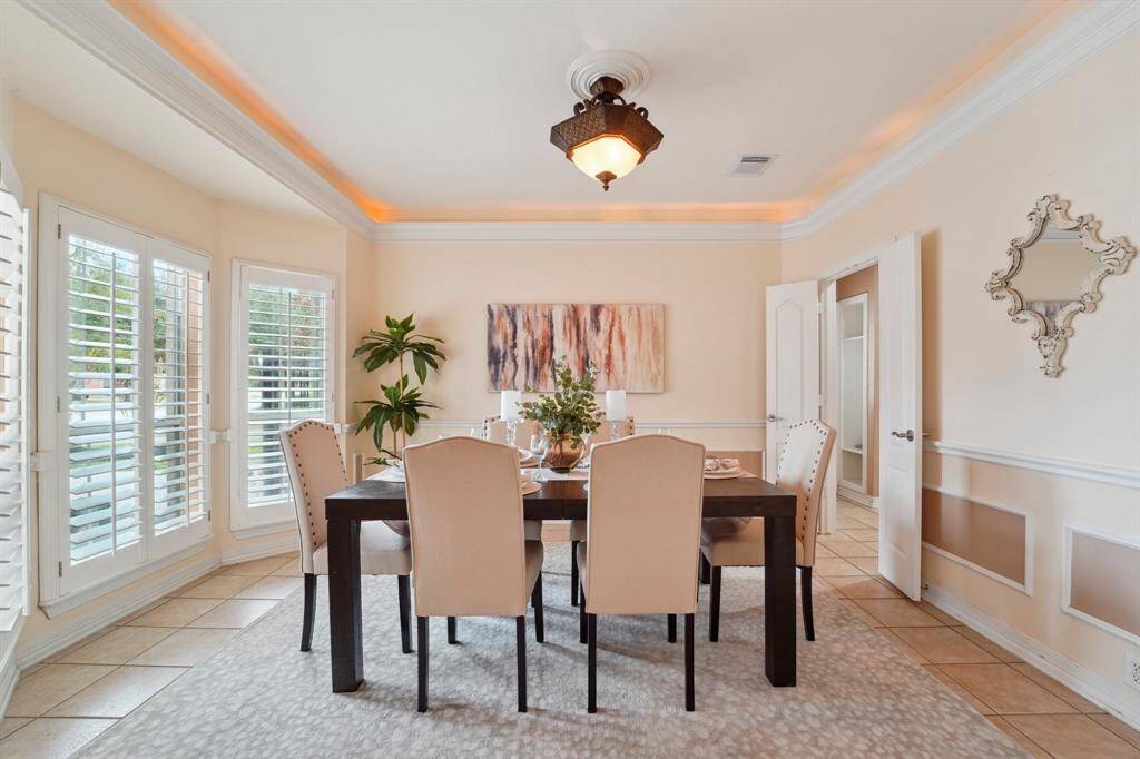 This elegant formal dining room sets the stage for both lavish dinner parties and casual gatherings. This space offers tile flooring, designer paint with picture, chair, and crown molding with up-lighting, wood shuttered windows, and a stylish chandelier.