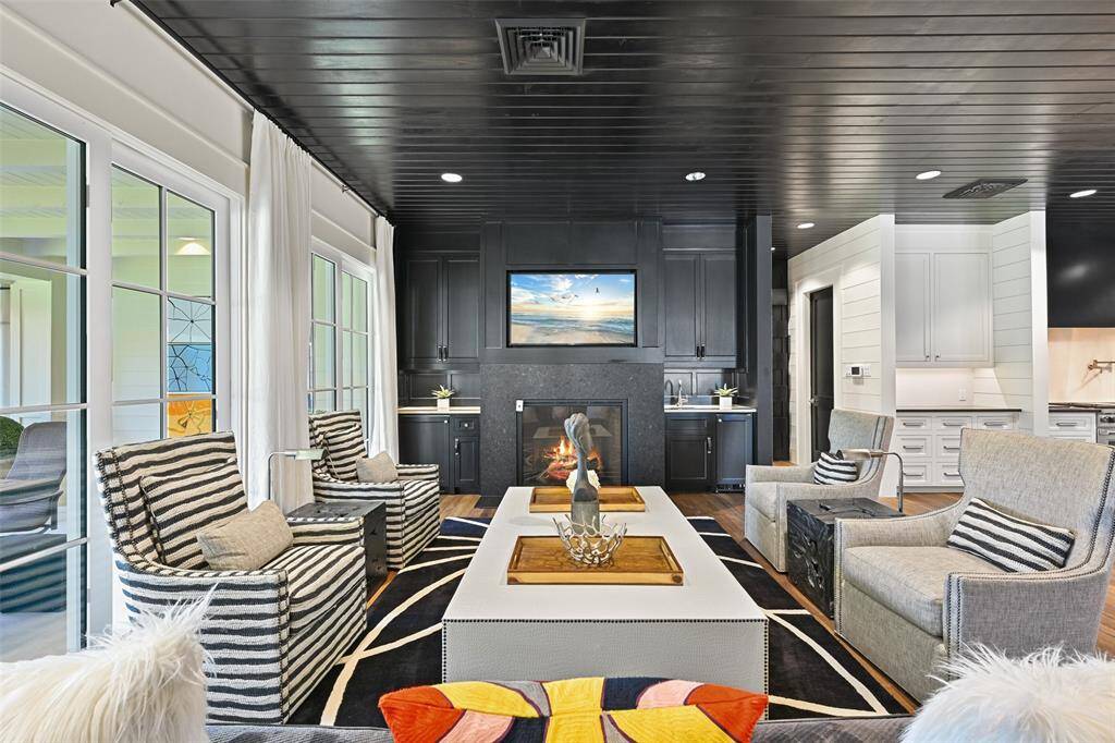Located just off the kitchen, the family room offers a cozy yet sophisticated retreat for relaxation and entertaining. The bold, dark fireplace feature, complimented by wall to wall sliding doors, creates a sense of drama and elegance. The views of the outdoors allow natural light to flood the space, enhancing its warm ambiance.