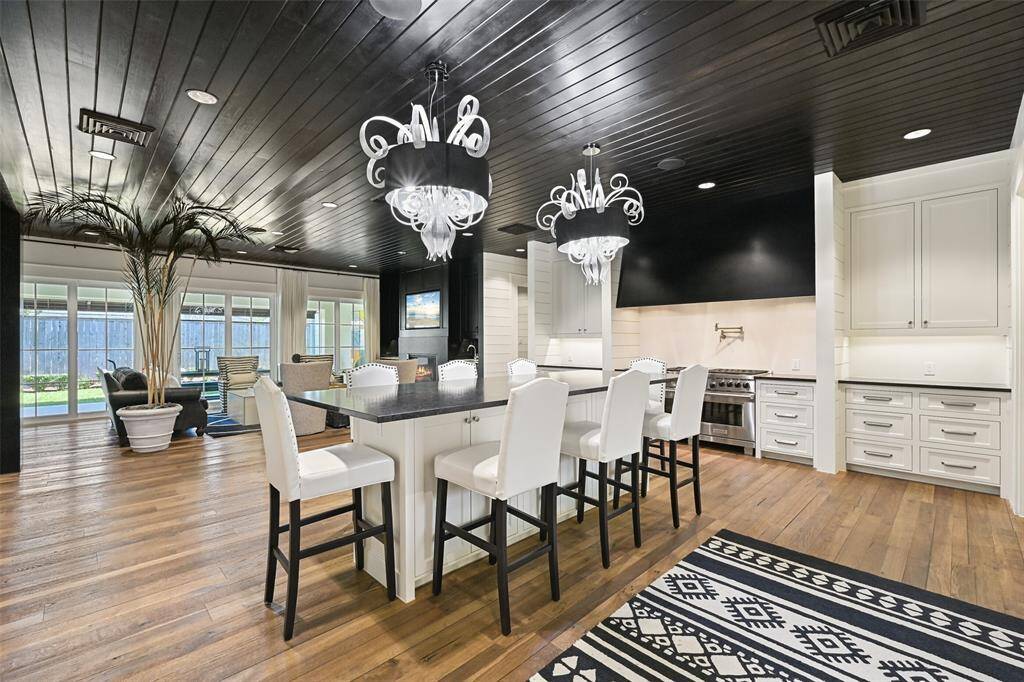 The kitchen's spacious island, topped with rich granite, provides ample space for meal preparation and entertaining. Dual Ralph Lauren pendants illuminate the space, complimenting the rich reclaimed wood floors.