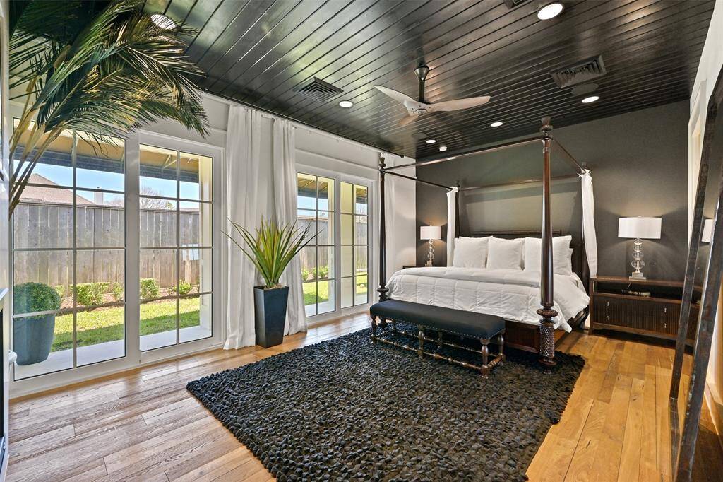 A luxurious retreat, the primary bedroom features elegant wood ceilings, wall-to-wall glass sliding doors with electric drapes that open to a private patio.