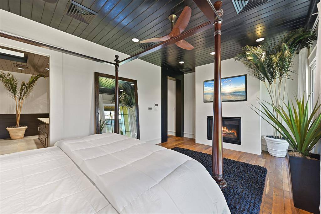The fireplace and built-in tv enhance the serene atmosphere, complimented by the rich wood floors and natural light.