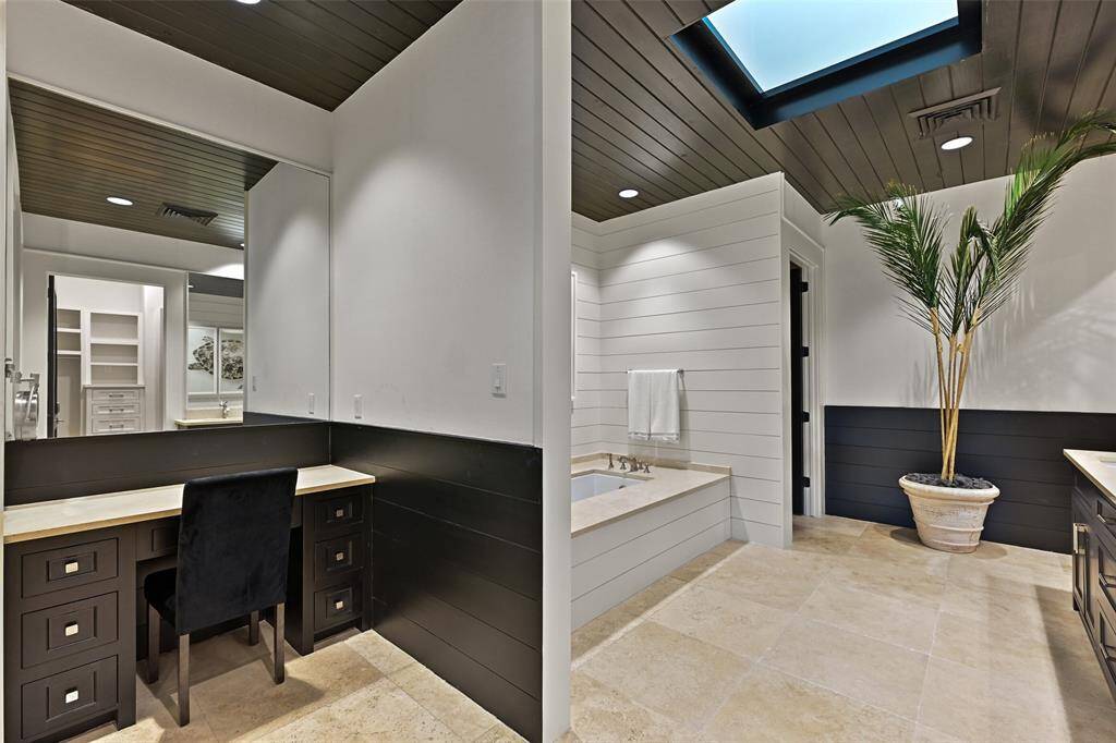 The primary bathroom offers functionality and luxury with a vanity area, large soaking tub and sky light to allow for natural lighting.