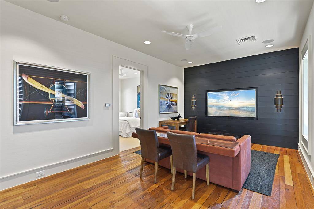 The second floor game room/living room offers a versatile space with large windows that fill the room with natural light. The room features a bold, black shiplap wall adorned with stylish black wall sconces adding a touch of luxury and warmth, while its neutral walls create a clean and inviting atmosphere.