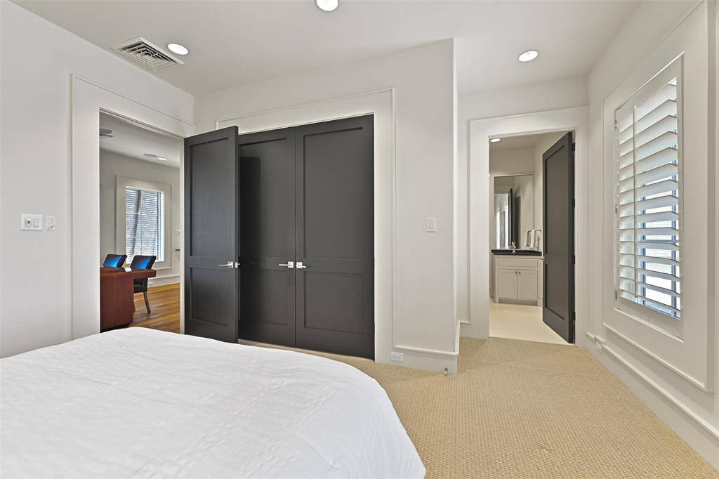 Elegant trim work and dark painted doors add a touch of sophistication, while plush carpet ensures comfort underfoot. This bedroom seamlessly combines luxury and tranquility, making it an inviting personal haven or for guests within the home.