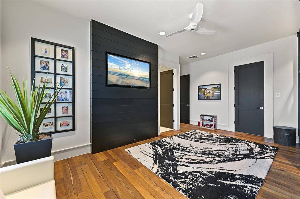 The Bunk room excudes a unique charm with a black built-in ship lap tv feature, warm wood floors, recessed lighting, loads of natural light and sleek fan.