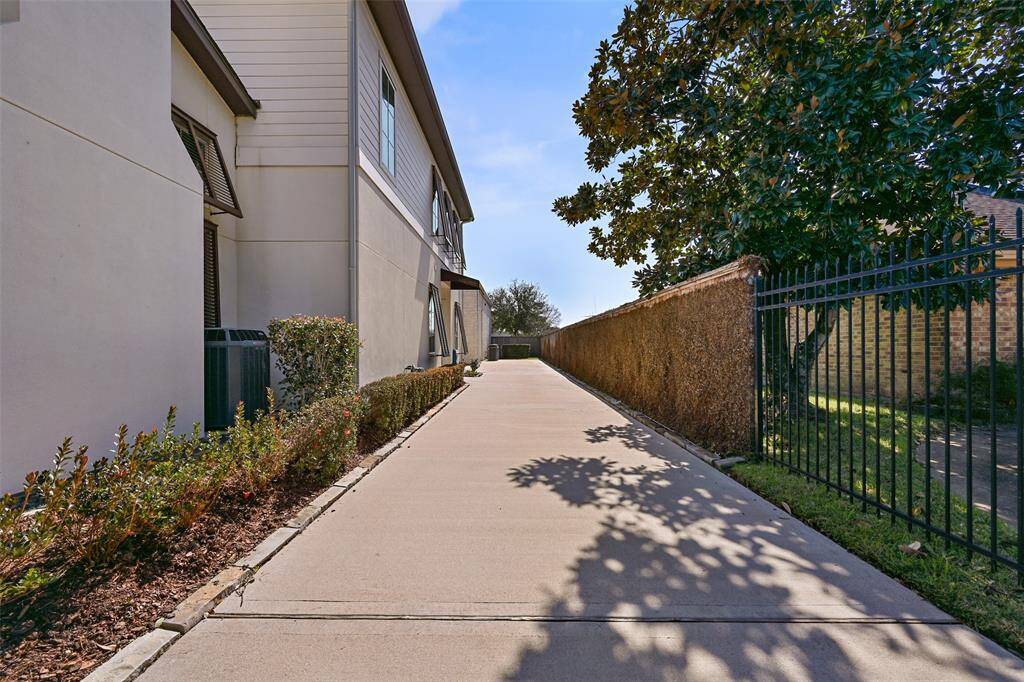 Behind the private gates of the driveway, a long stretch of driveway leading to the side loading garage and hangar towards the rear of the property.