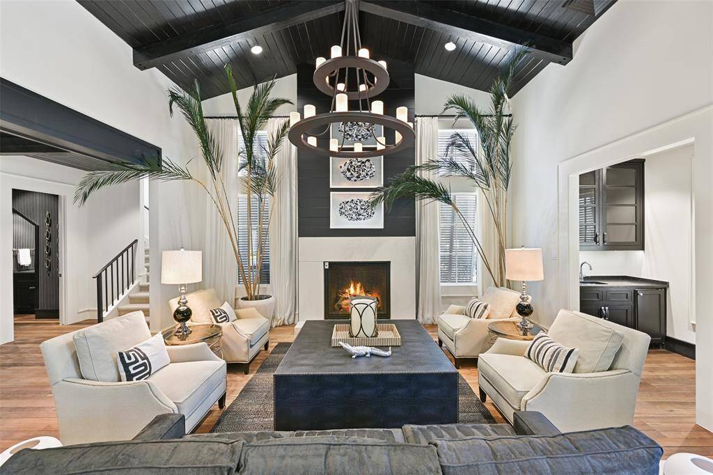 Making a grand first impression, the great room features a warm seating area with striking fireplace, dramatic painted vaulted wood ceilings & grand chandelier.