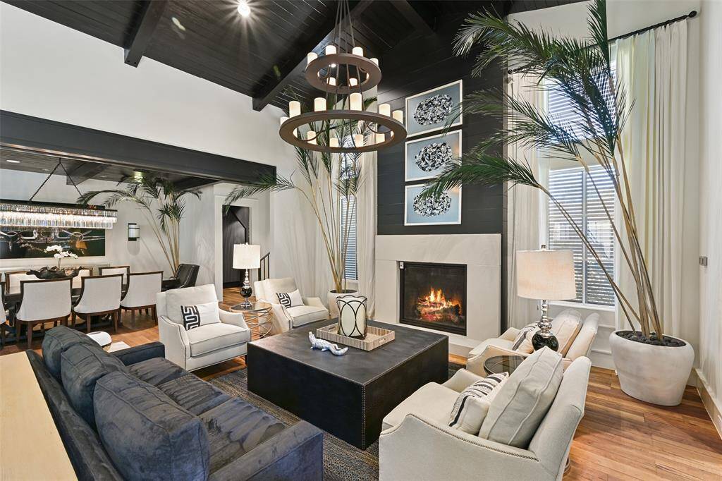 Exuding elegance, the stunning seating area is framed by expansive floor-to-ceiling windows that invite natural light to pour in. The central fireplace anchors the room, creating a warm and inviting focal point.