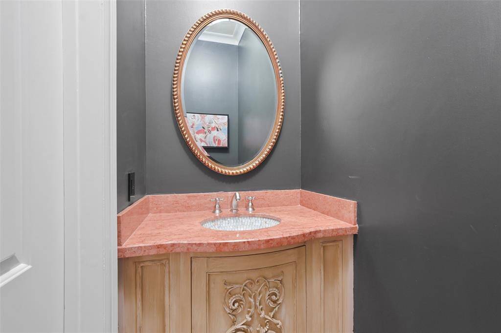 The powder room features furniture quality cabinetry with mosaic tile sink and natural stone counter.