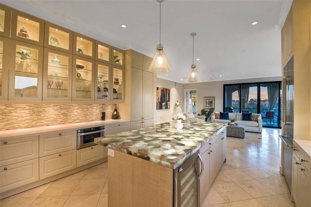 The island kitchen is open to the living room. Downlit glass front cabinets, under counter lighting and up lit onyx island counter top create an elegant environment for entertaining.