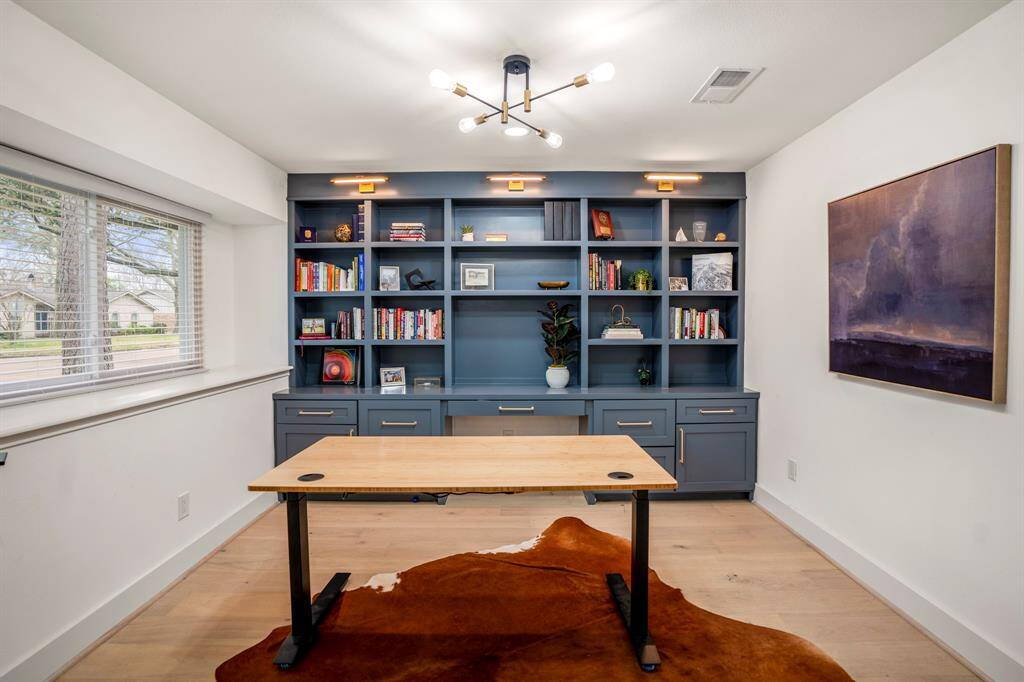 Work in style! This chic home office features wood floors, custom built ins, and plenty of natural light—perfect for productivity and inspiration.