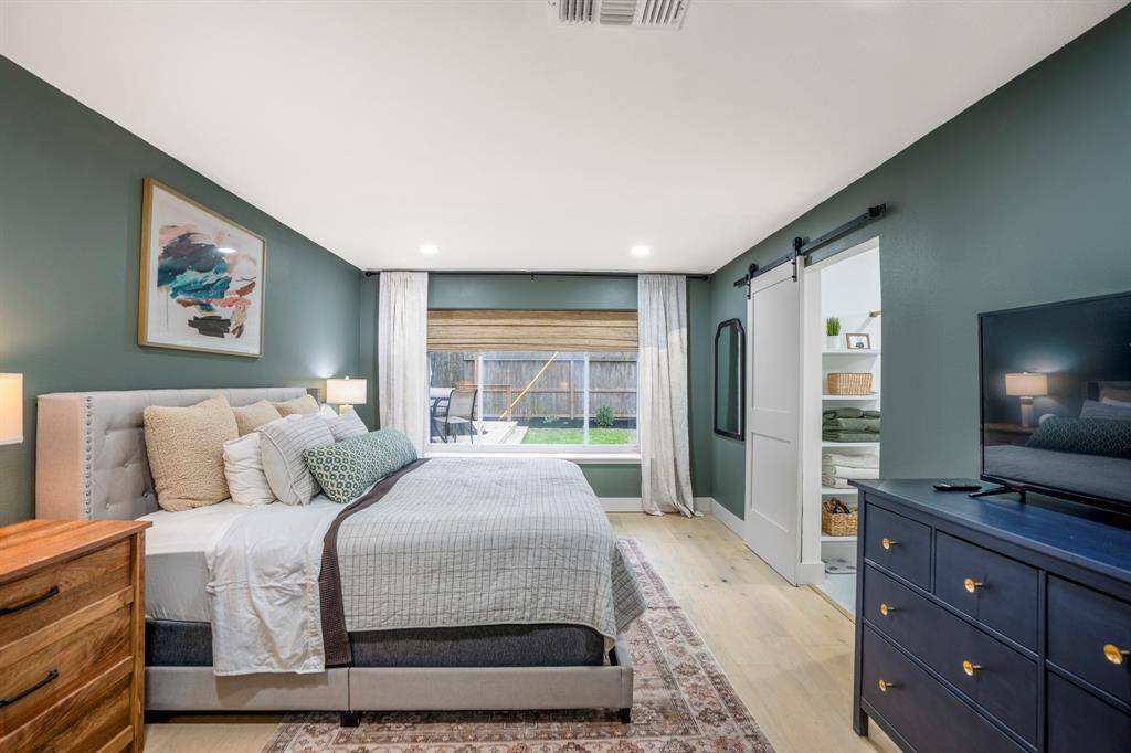 Serene sophistication at its finest! This stunning primary bedroom blends cozy comfort with modern elegance — featuring calming green hues, a chic barn door leading to the primary bathroom, and a flood of natural light from the large picture window. A true retreat to relax, recharge, and unwind.