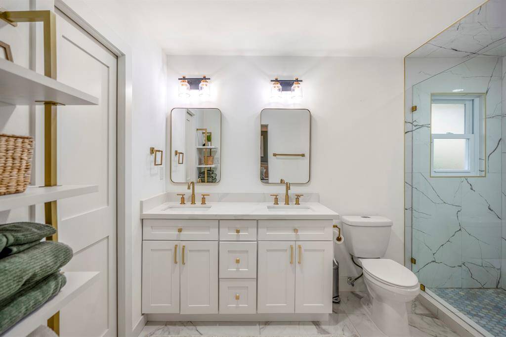 You'll love getting ready in this light and bright primary bathroom! The primary bathroom includes a large vanity with dual sinks, framed mirrors, quartz countertops, and brushed gold plumbing features and hardware.