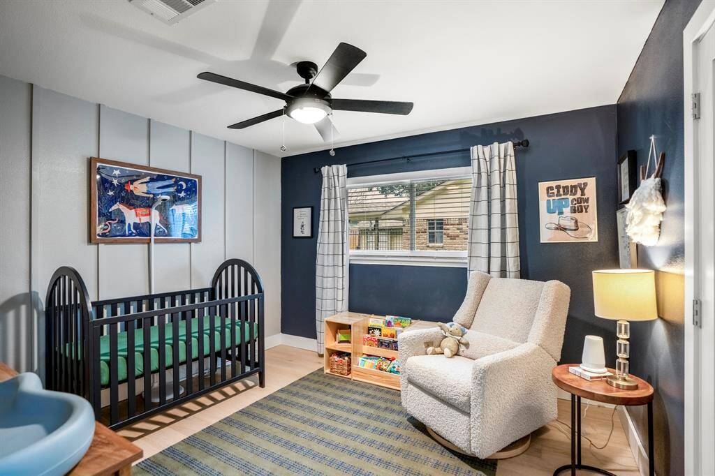 Another spacious secondary bedroom with a bold accent wall and paint, oak floors, bright natural light, and above ceiling fan.