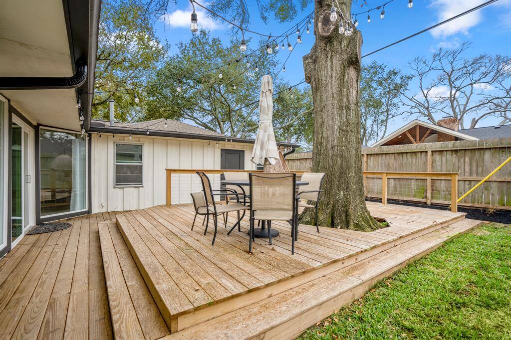 The sellers added the perfect custom deck to this backyard! It's complete with string lights, railing, and incorporates the enchanting tree.