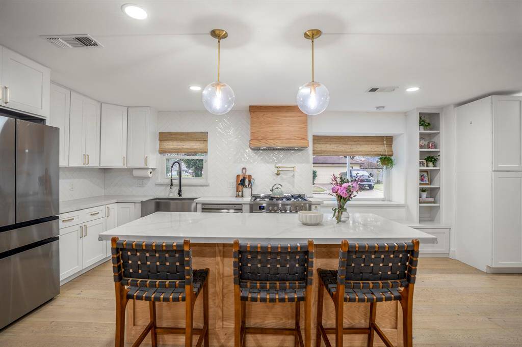 The kitchen boasts a deco wood paneled island surround with beautiful quartz countertops. Upgraded in stainless steel appliances, a 5 burner gas stove, and sleek white cabinets, this kitchen is ideal for cooking for the whole family or hosting holidays!