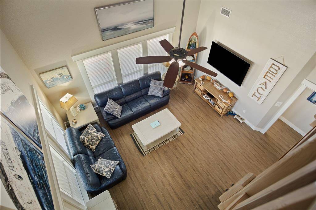 This well-lit living room with high ceilings and hardwood floors is perfect for rainy days at the beach.