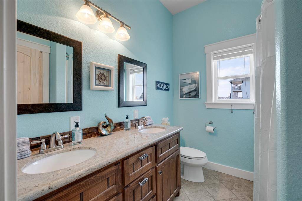 Main floor bathroom features a double sink vanity with a granite countertop and wooden cabinets.