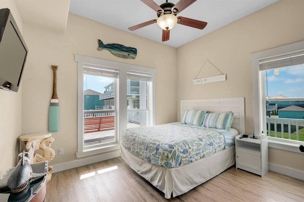 This cozy bedroom features a queen bed with large windows offering plenty of natural light and views of the deck.
