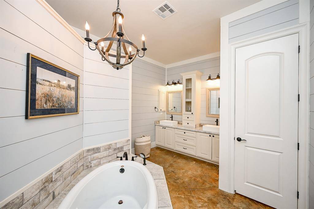 Just as impressive as the primary bedroom is the primary bath.  Shiplap designer touch and designer backsplash is a feature to go along with decorative backsplash, painted concrete flooring, a separate soaking tub, dual sinks, plenty of storage cabinets and drawers, dual mirrors, accent lighting, and recessed lighting.  There is one additional element....