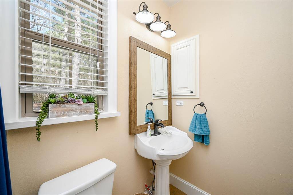 Just off the second bedroom is an adjacent bathroom with window, plantation blinds and a view of the side of the fenced backyard, a shower tub combination, and a designer sink and lighting.
