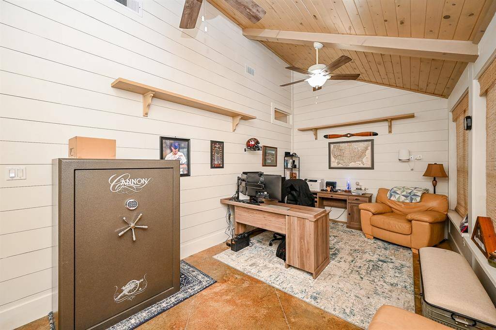 Located just off the family suite is a room designed for dual purpose.  Shown here this room is used as a home office.  It can also double as a sunroom.  The shiplap design is carried thru into this room along with the designer wood ceiling.  A pair of ceiling fans and the painted concrete floor complete this room.