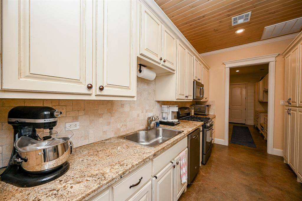 Remember the barn doors that were shown just to the right of the family room?  Walk through them and you enter what could be a second separate living area.  Heat and air can be controlled separately.  The first room you enter is a second kitchen.  This area is complete with the same painted concrete flooring, granite counter tops, dishwasher, gas stove and oven, microwave, and plenty of storage.  Doors just to the right allow for entrance to the living suite in this section of the home.