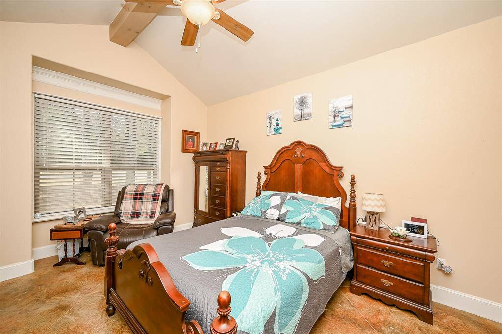 This second living area features two separate bedrooms.  The first features painted concrete flooring, dual windows with plantation-style blinds and plenty of natural light and a view of the front yard, vaulted ceiling, ceiling fan, and smoke detector.
