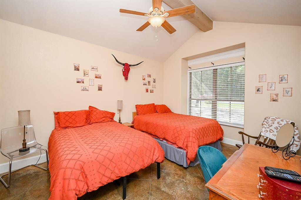 A second bedroom, located off the opposite side of the gathering area also features the same painted concrete flooring, dual windows with plantation-style blinds and a view of the front yard, vaulted ceiling, ceiling fan and smoke detector.