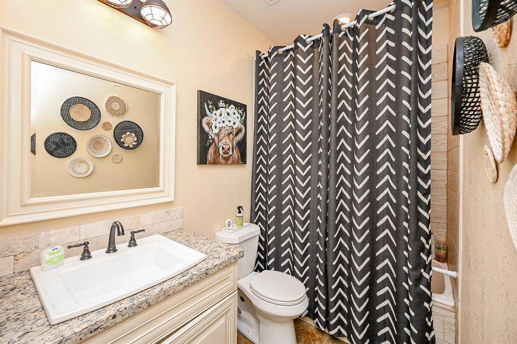 A second bathroom contains a shower and tub combination, single sink with granite counter top, designer lighting, and shiplap designer tile backsplash.