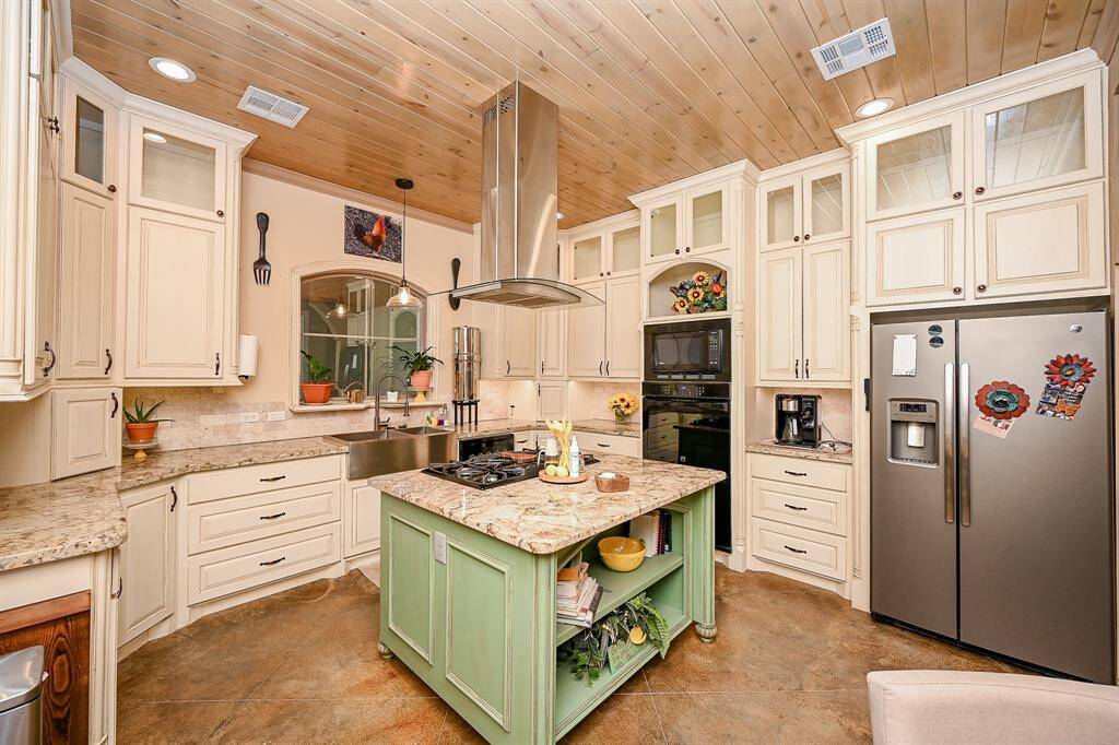 What can't you create for your family from this kitchen? An island with cooktop and vent is but a start. Microwave, dual oven, a large refrigerator, dual sink, and an eye-catching number of drawers and cabinets provide storage that a chef would envy. Painted concrete floor catches any messy mistakes. Granite counter tops, a designer wood ceiling with recessed lighting, and even a window that allows for a peek at the outside covered patio complete this room.