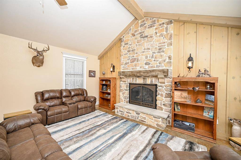 Just a few steps from the more formal dining table option is a second family room.  The primary feature is a stunning stone gas log fireplace with wood mantle and wood accent wall.  A vaulted ceiling, ceiling fan, and recessed lighting create a comfortable area to gather.   As is the case with the other rooms, this one also features the same stained concrete flooring.