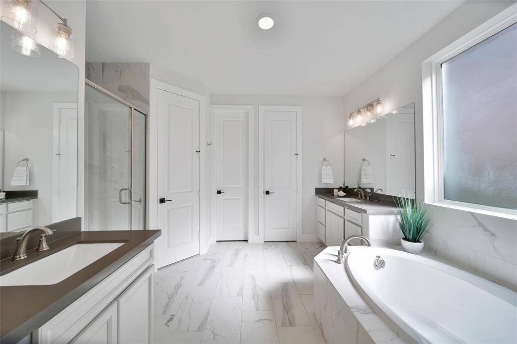 Natural materials and neutral colors combine to create a spa like space in the primary bath. Spacious primary closet runs across the back width of the bathroom.